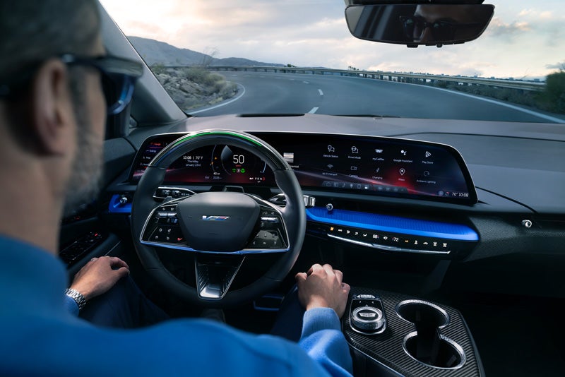 Front View of the 2026 OPTIQ-V Driving Through the Dusk Utilizing its Headlights | Tom Clark Cadillac in Denton TX