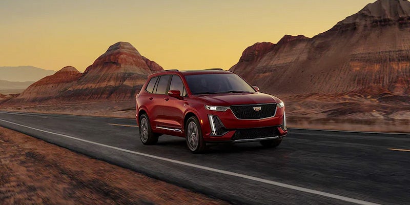 Red Cadillac XT6 running on road from mountains