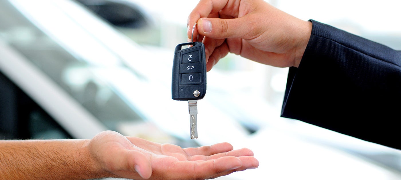 a sales representative handing off car keys - Tom Clark Cadillac in Denton TX